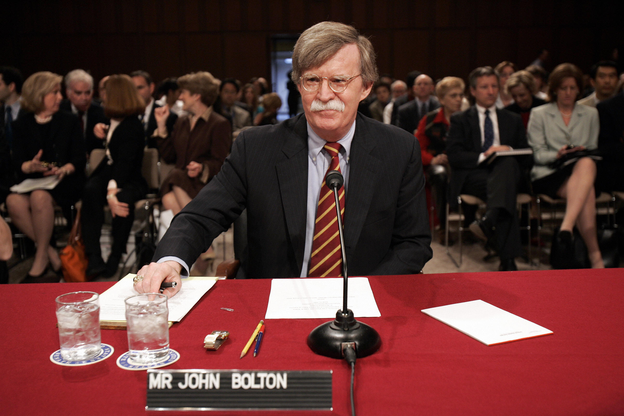 John Bolton takes his seat before a conf