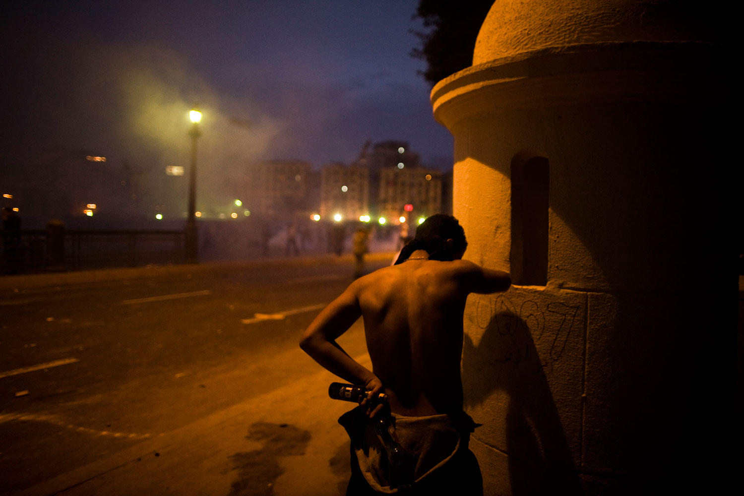 A protestor takes cover behind a wall during clashes with police.