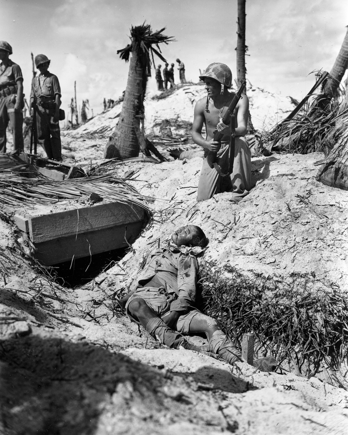 A Marine poses near a Japanese sniper he killed during the invasion of the Gilbert Islands in World War II, November 21, 1943.