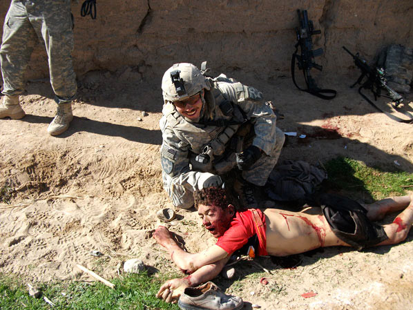 This image, published by Rolling Stone, shows the body of Gul Mudin, the son of a farmer, who was killed on Jan. 15, 2010. Cpl. Jeremy Morlock, a member of the  kill team  is posing next to him.