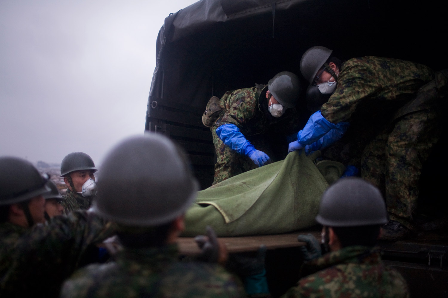Soldiers pull a victim into a military truck in Natori on March 15, 2011