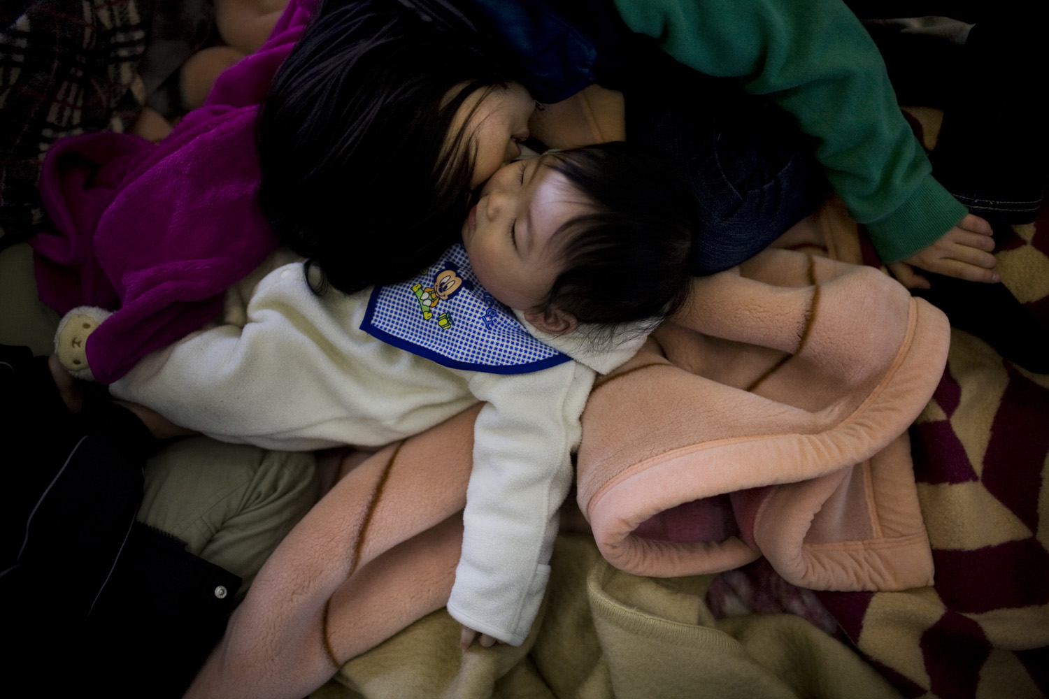 Two sisters seek shelter in a school gymnasium after being evacuated from Minamisoma, near the Fukushima nuclear plant, on March 16, 2011