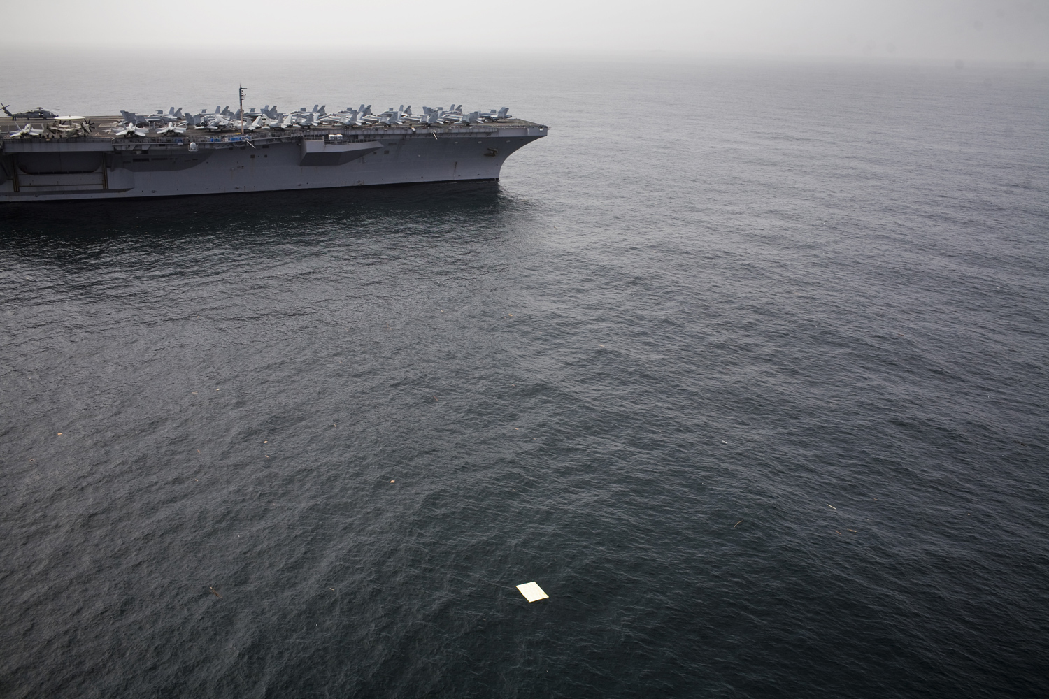 Debris from the aftermath of the Tsunami is visible in the waters near the aircraft carrier USS Ronald Reagan stationed off the coast of Japan's Sendai region. March 20, 2011