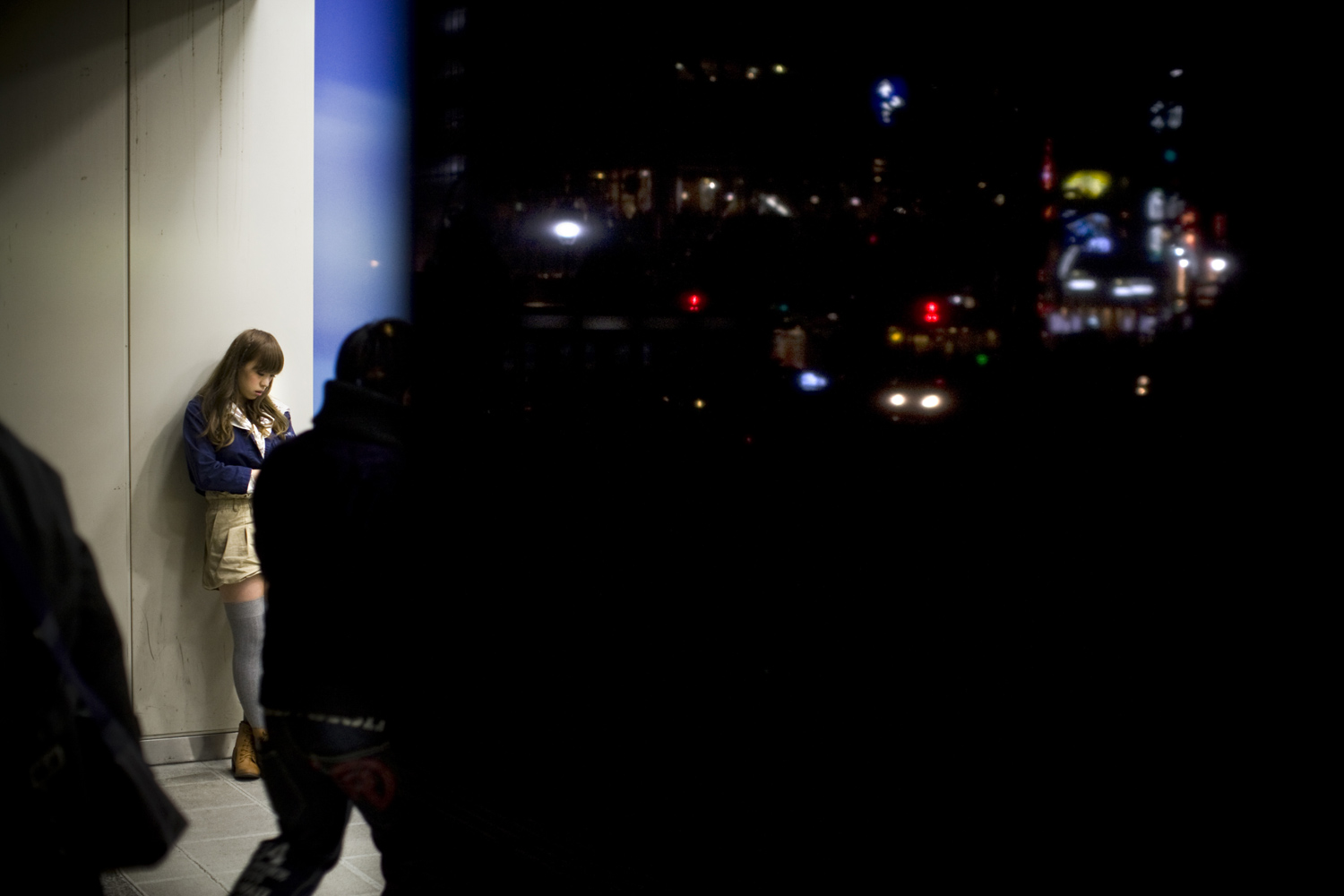 A woman waits at the entrance to the Shibuya subway station in Tokyo while the usually vibrant streets are mostly dark due to the power cuts since the earthquake. March 21, 2011