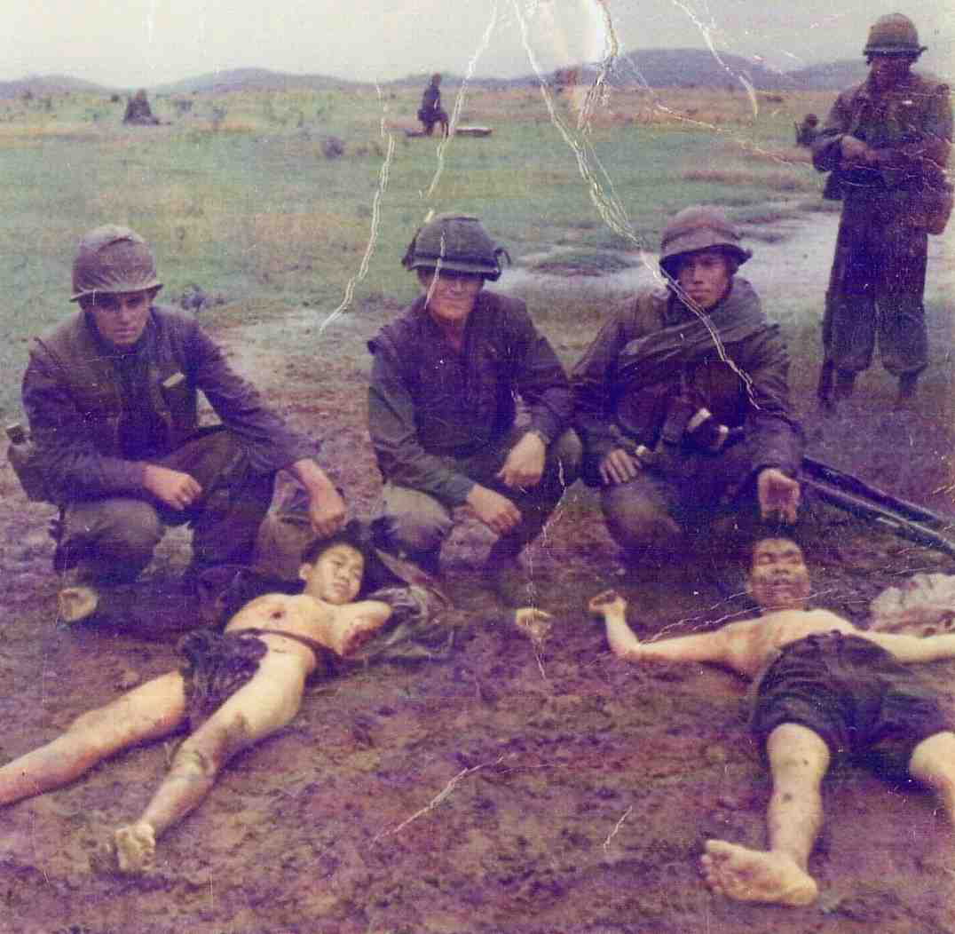 American soldiers pose with dead Vietnamese after a mission during the Vietnam War in 1968.