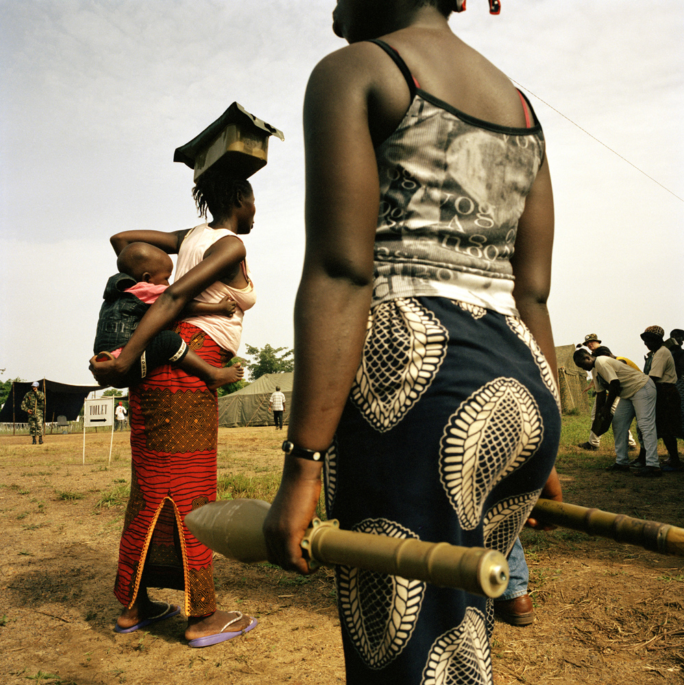 Women bring rocket-propelled grenades and ammunition to an UNMIL disarmament point during the UN-sponsored DDRR (disarmament, demobilization, rehabilitation and reintegration) program. Tubmanberg, Bomi County, April 2004.