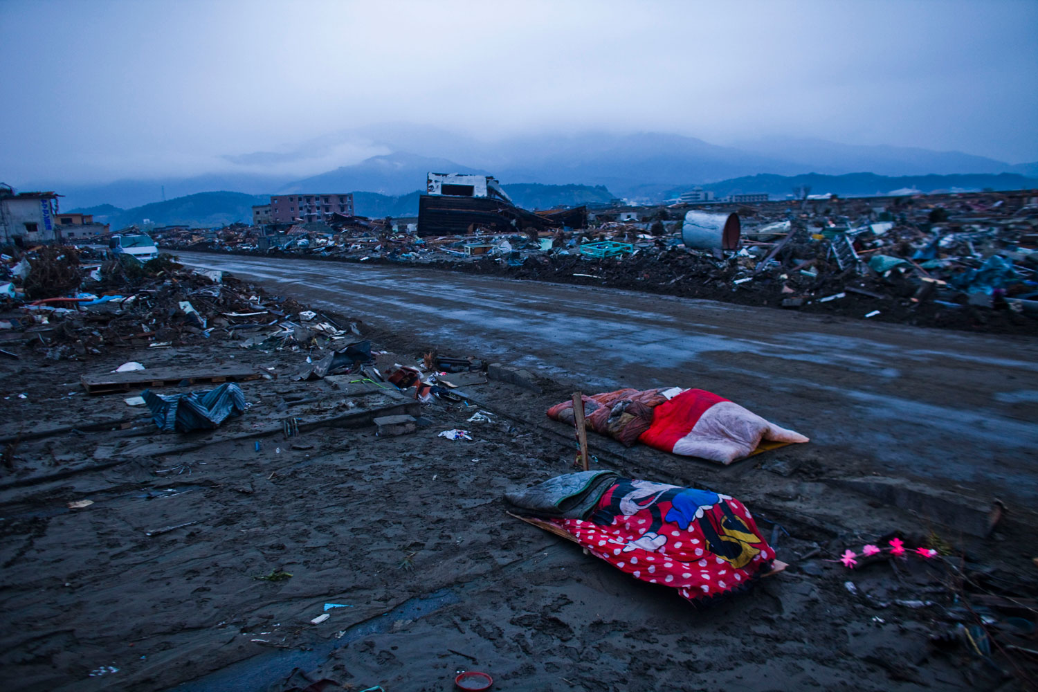 Two bodies are left covered by blankets near the rubble of Rikuzenmaeda, Iwate prefecture, Japan, March 15, 2011.