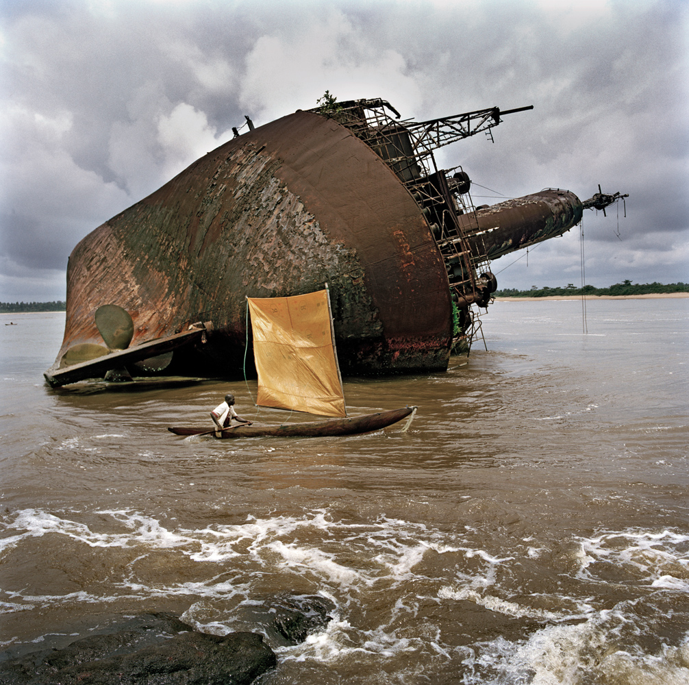 A fisherman passes a shipwreck near the port of Greenville. In the mid 1990s, a vessel arrived carrying an aid cargo of rice and fuel. The captain and crew left the ship when it developed a problem and was in danger of sinking. They returned the next day to find that the whole cargo had disappeared and the ship had been ravaged. Greenville, Sinoe County, 2005.
