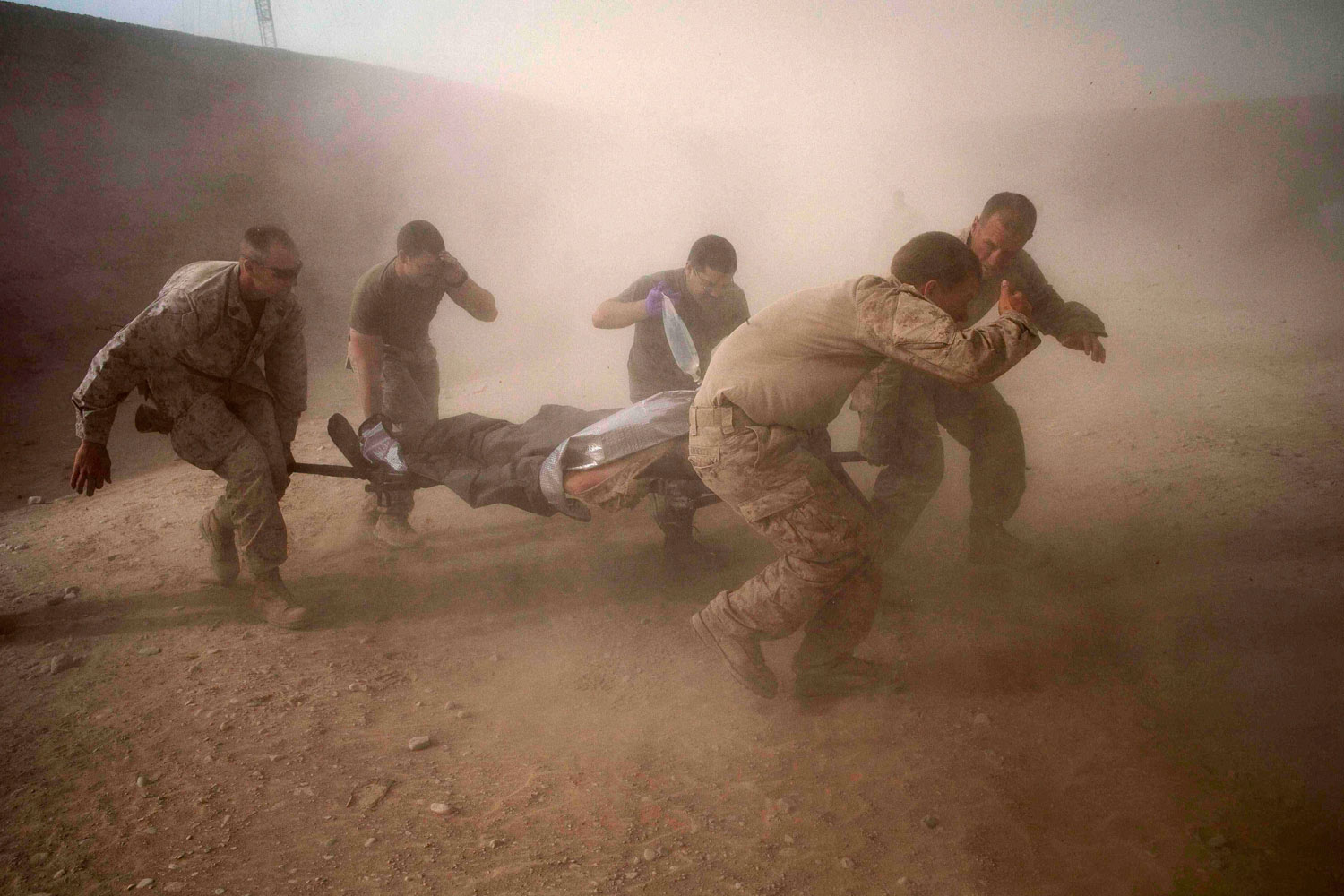 May 10, 2011.  U.S. Marines rush a wounded compatriot through a dust storm kicked up by a U.S. helicopter near Sangin, Afghanistan.