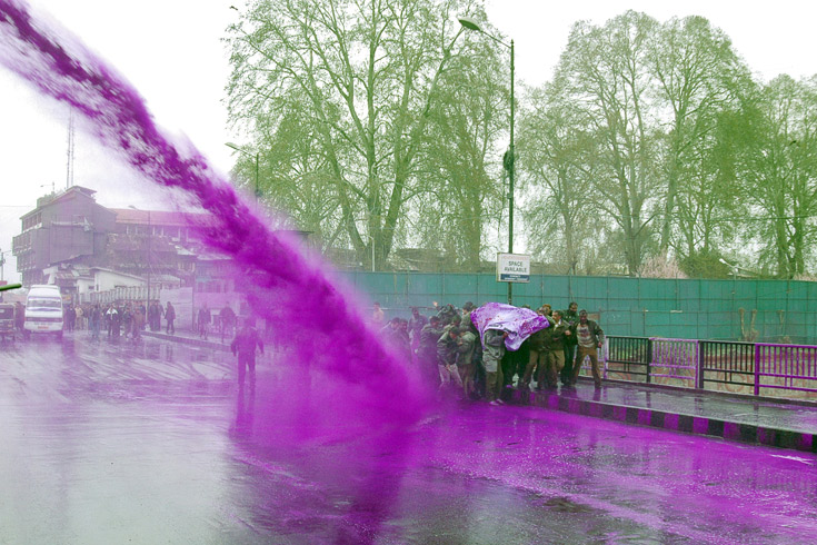 Indian policemen fire purple colored water from a water cannon on Kashmir government employees during a protest on April 06, 2011 in Srinagar.