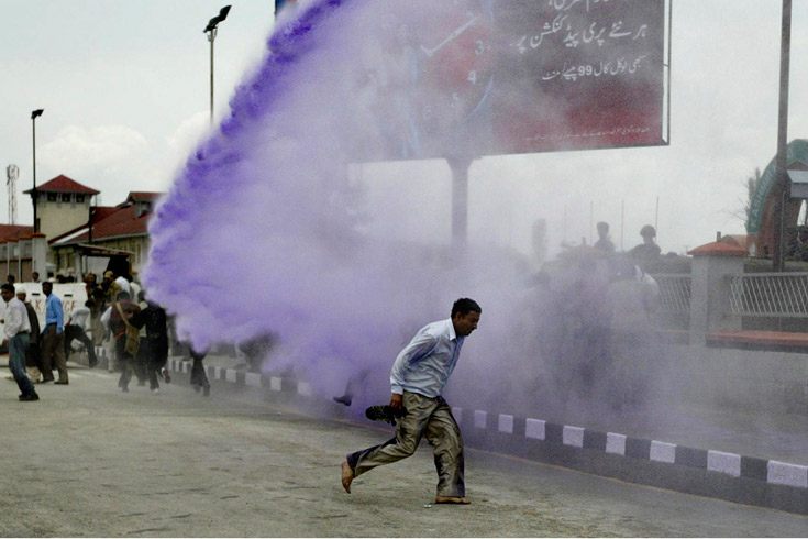 A Jammu Kashmir state government employee runs for cover as police use colored water cannons during a protest outside the civil secretariat in Srinagar, India, May, 5, 2008. The employees were demanding regularization of their jobs and a hike in their pay.