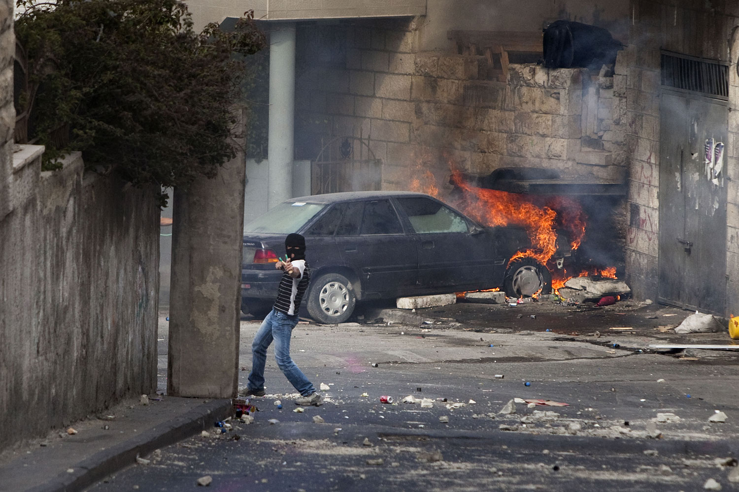 A Palestinian youth throws stones at Israeli police. Clashes erupted in East Jerusalem after Friday prayers and lasted several hours, before undercover police moved in to arrest the protesters.