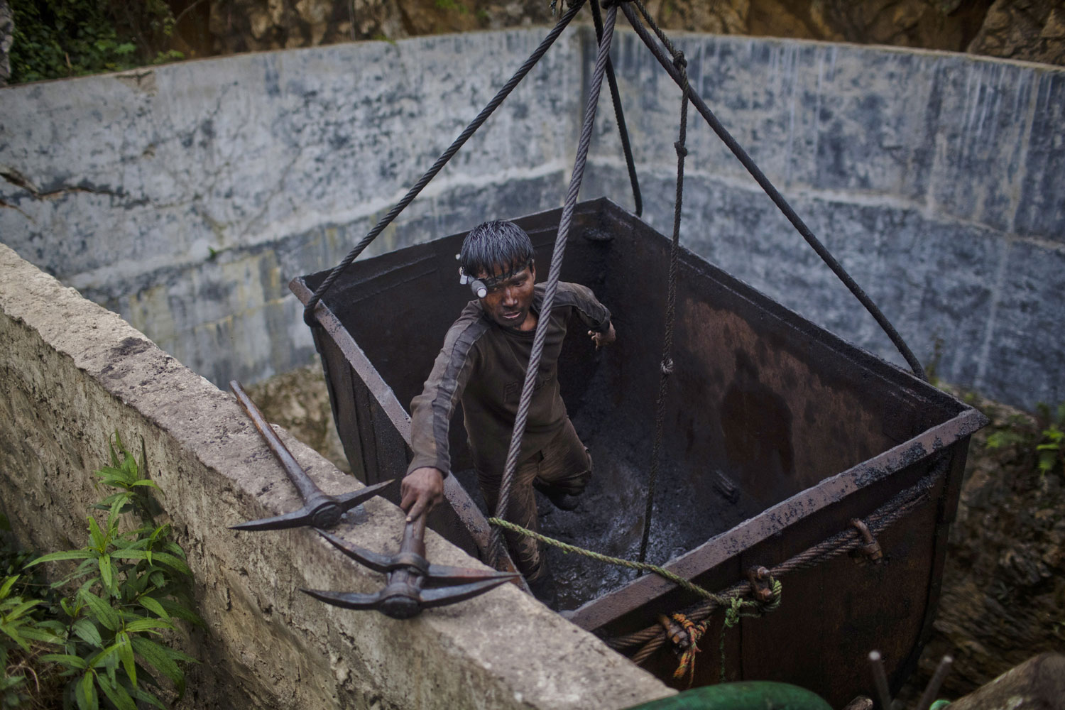 A miner unloads tools after being hoisted from the depths of a coal mine.