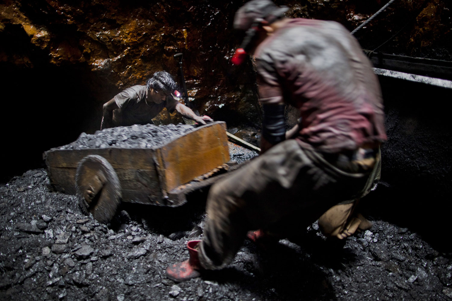 20 year old Anil Basnet pushes a coal cart, as he and a fellow worker pull coal out from the rat hole tunnel 300 ft below the surface.