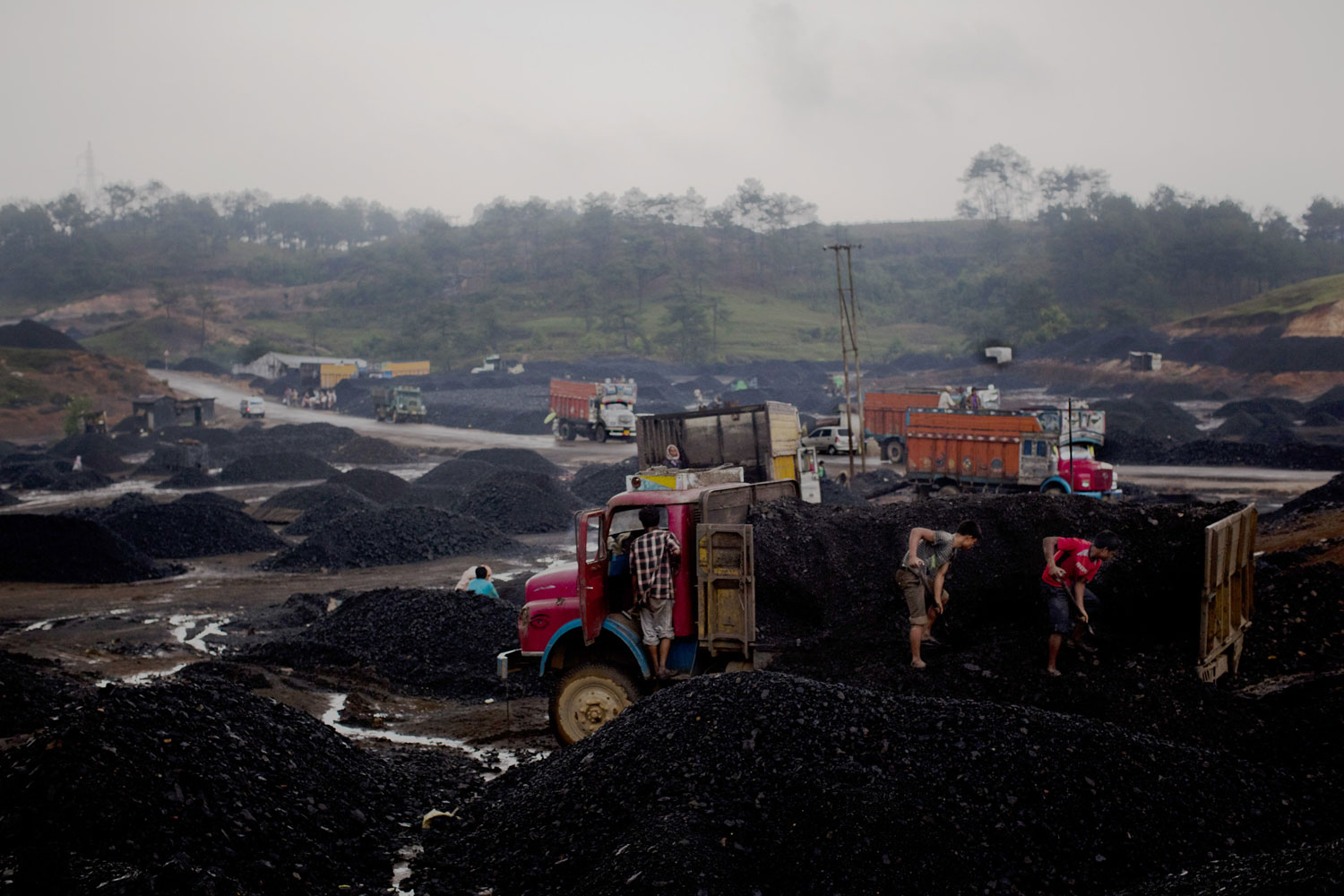 Workers load coal onto trucks at a coal depot. After traversing treacherous mountain roads, the coal is delivered to neighbouring Bangladesh and to Assam from where it is distributed all over India, to be used primarily for power generation and as a source of fuel in cement plants.