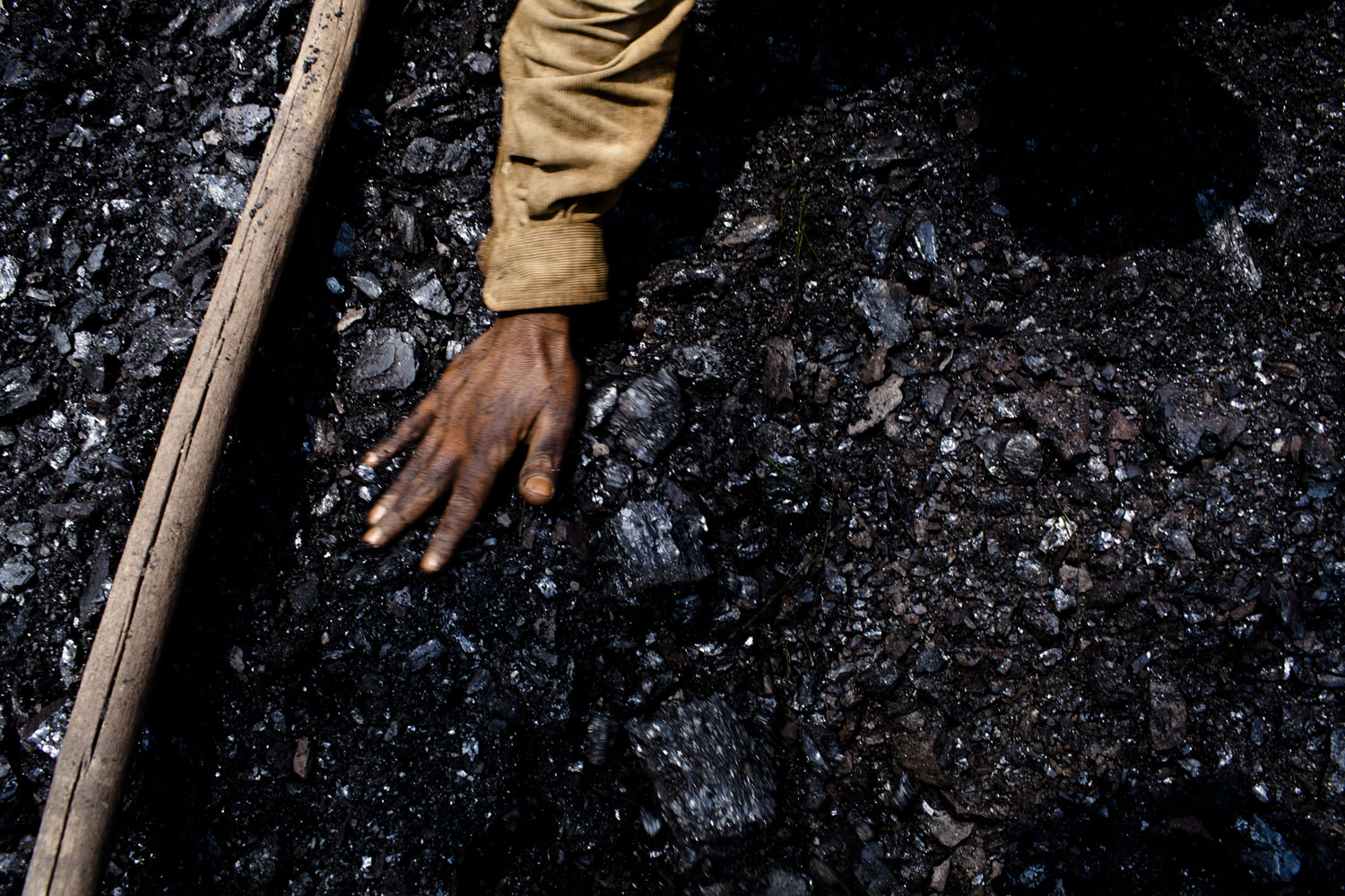 A worker, levels out the coal in a crate.