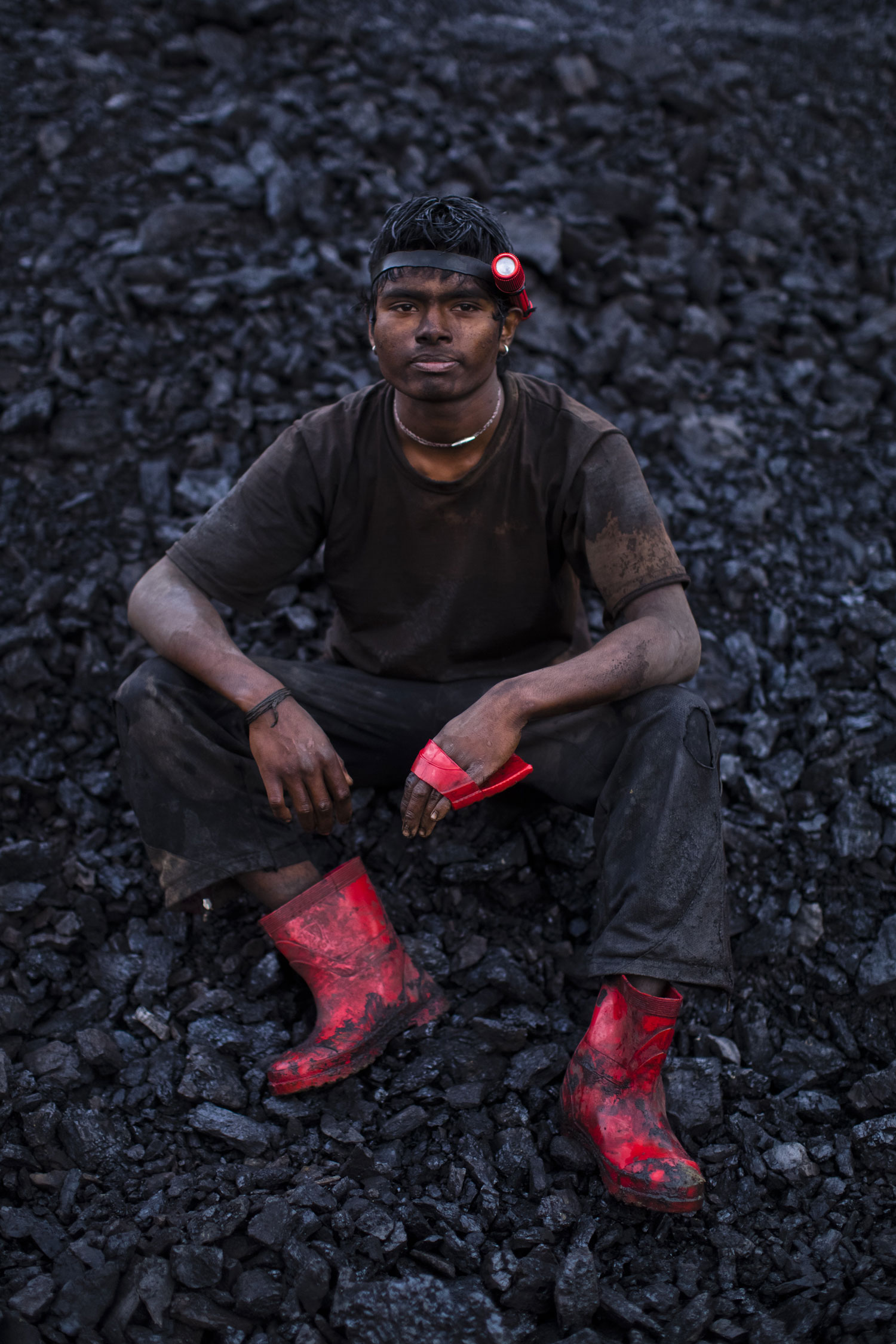 20 year old Anil Basnet, sits for a portrait, above the coal mine where he works