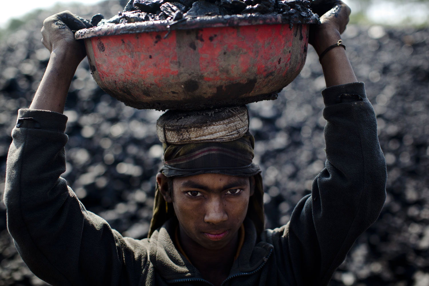 12 year old Abdul Kayum from Assam pauses for a portrait, whilst working at a coal depot carrying coal to be crushed