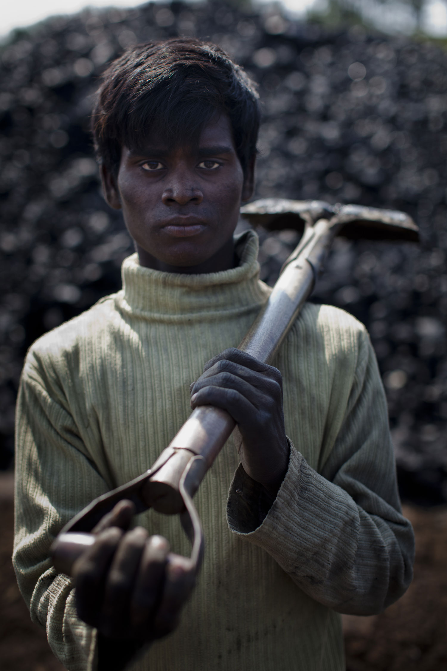 16 year old Rafaqui Islam, from Assam, poses for a portrait, whilst working at a coal depot shovelling coal to be crushed.