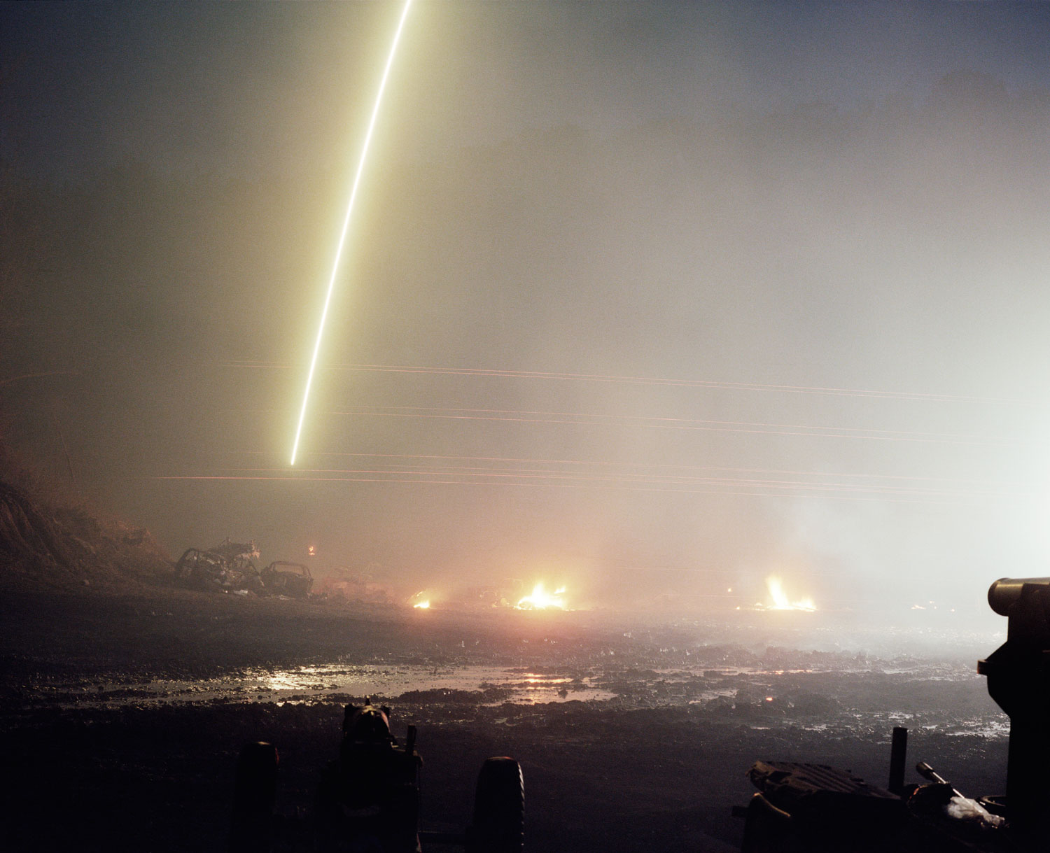 Fires and tracer rounds light up the night.