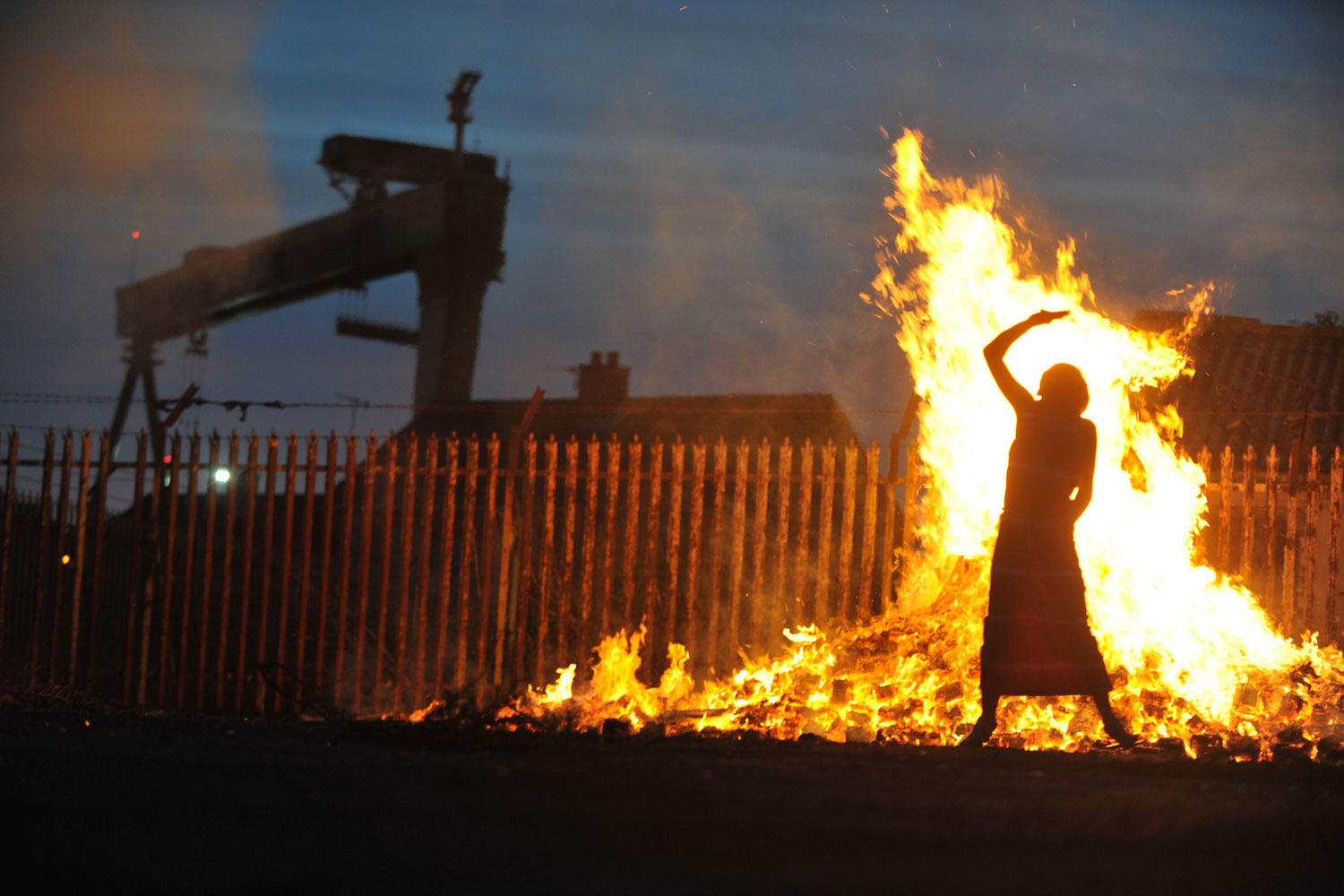 July 11, 2011. Children play around a bonfire lit in the shadow of a shipyard to celebrate the start of the loyalist Twelfth of July Celebrations in Belfast, Northern Ireland. Bonfires are traditionally lit in protestant areas on the 11th of July to mark the start of the Twelfth Celebrations. The cranes in the distance are in the Harland and Wolfe shipyard where the Titanic was built.