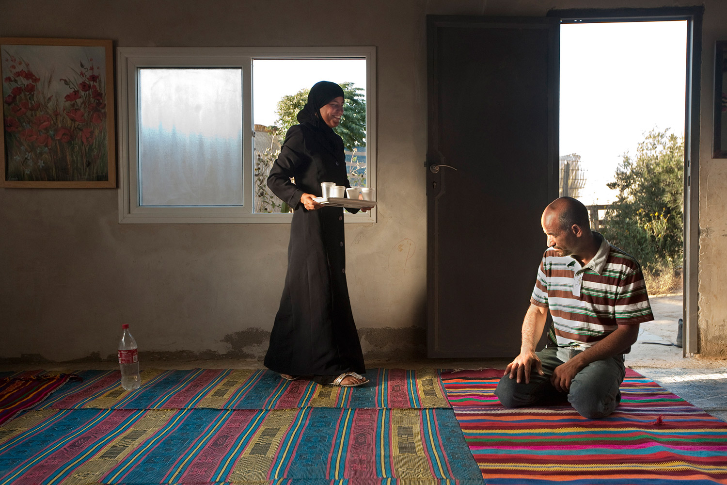 Iman Iben-Atami, 17, serving her father in the guest-room of their home in the unrecognized Bedouin village Hashem Zana. The Bedouin society is very traditional. Women are expected to follow a very strict lifestyle and be obedient to the will of their father or husband.
