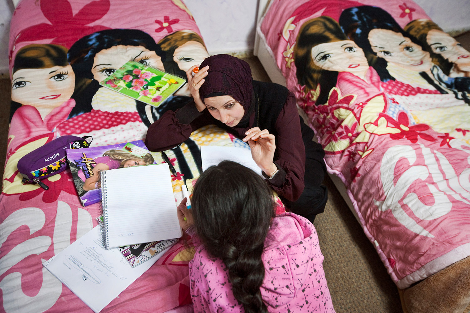 Angham Amin Issa, 18, top, helps her sister Johaina,10, with her homework. Most Arab families have many children, forcing the older to help their younger siblings.