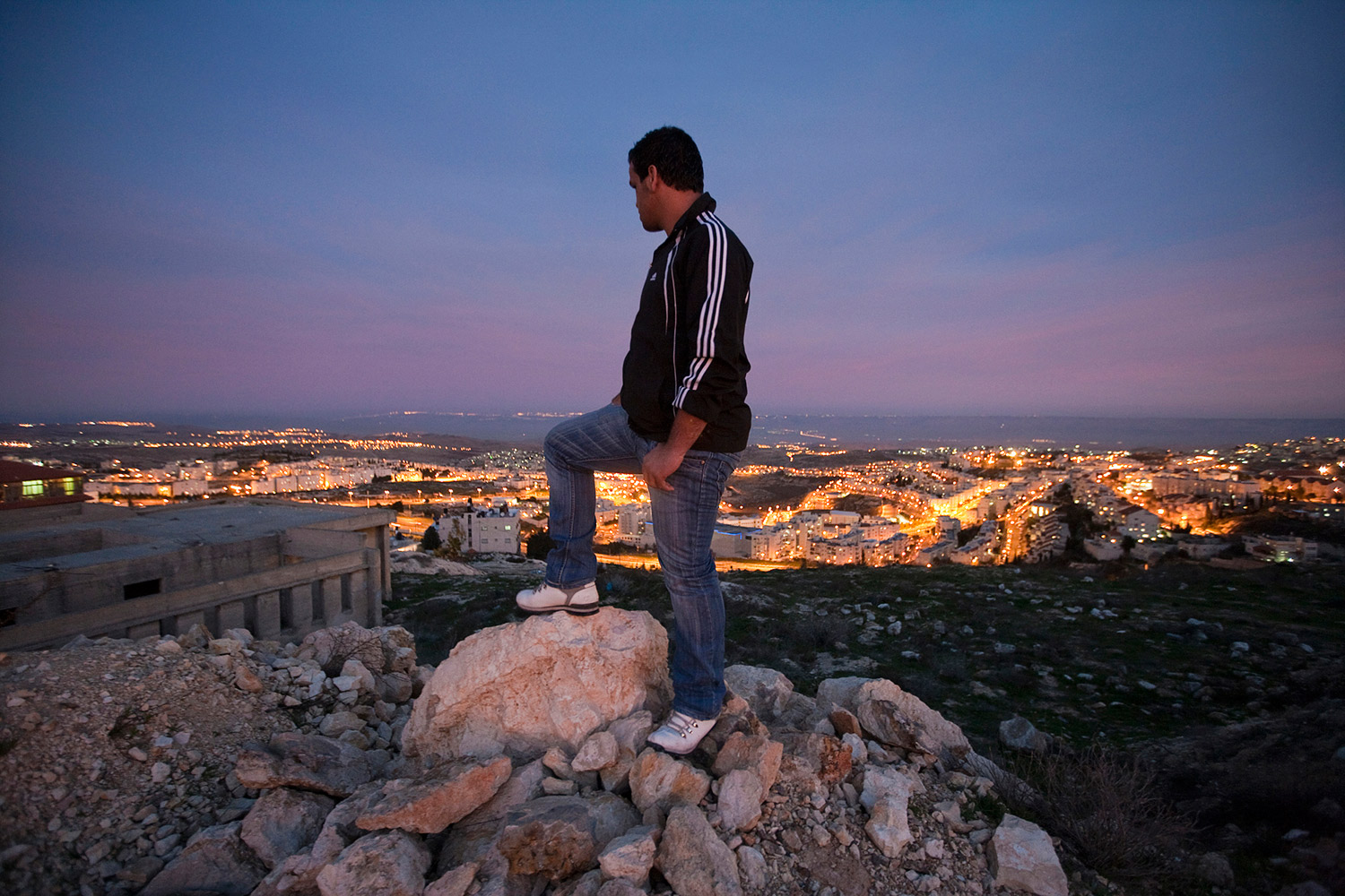 Samed Awad, 18, watching night fall over the Jewish neighborhood Givat Zeev from a hill next to his home in East Jerusalem. Samed says his family tries to have as little contact as possible with the Jewish residents since they want to avoid any unnecessary trouble.