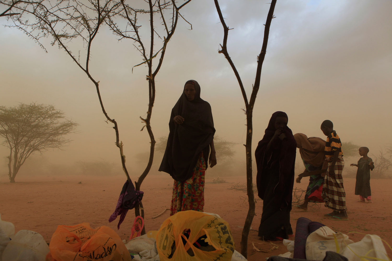 July 10, 2011. Members of a Somali family are overtaken by dust as they try to build a makeshift shelter on the outskirts of the Dagahaley camp, the world’s largest refugee settlement, outside Dadaab, Kenya. The drought in Somalia has been called the worst humanitarian disaster in the world by U.N. officials.
