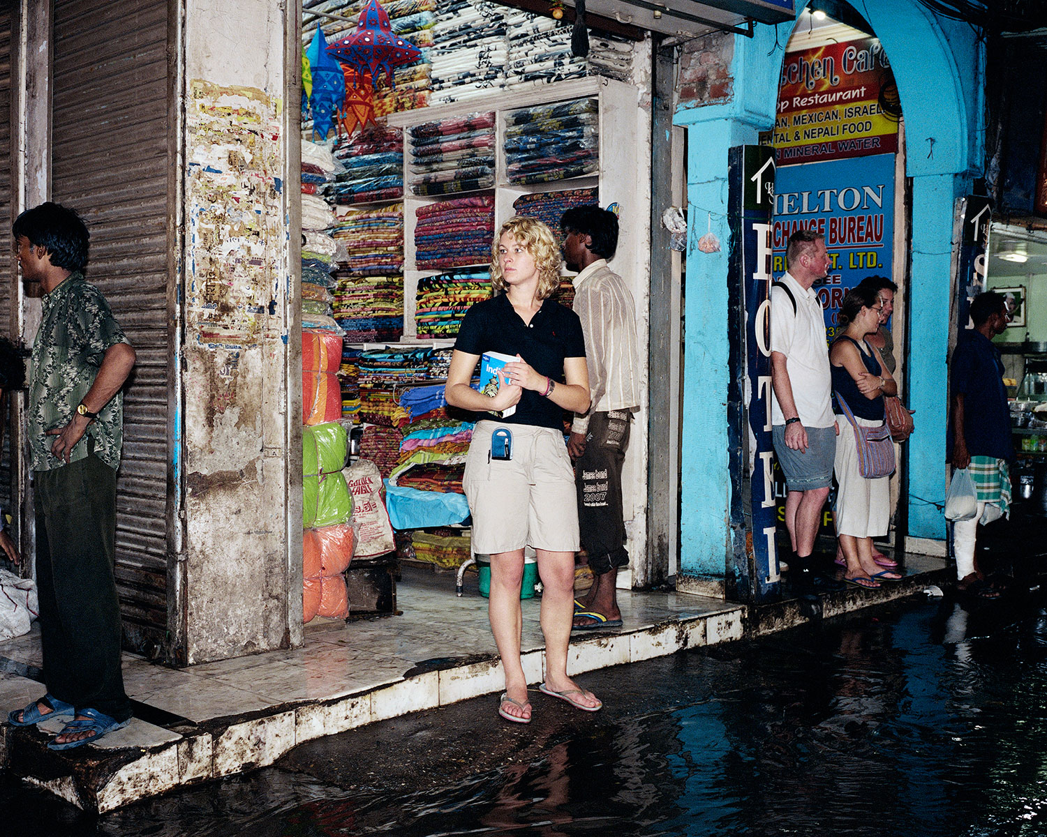 A backpacker holds her Lonely Planet Travel Guide on a street flooded by monsoon rain in Delhi, India, July 2007.