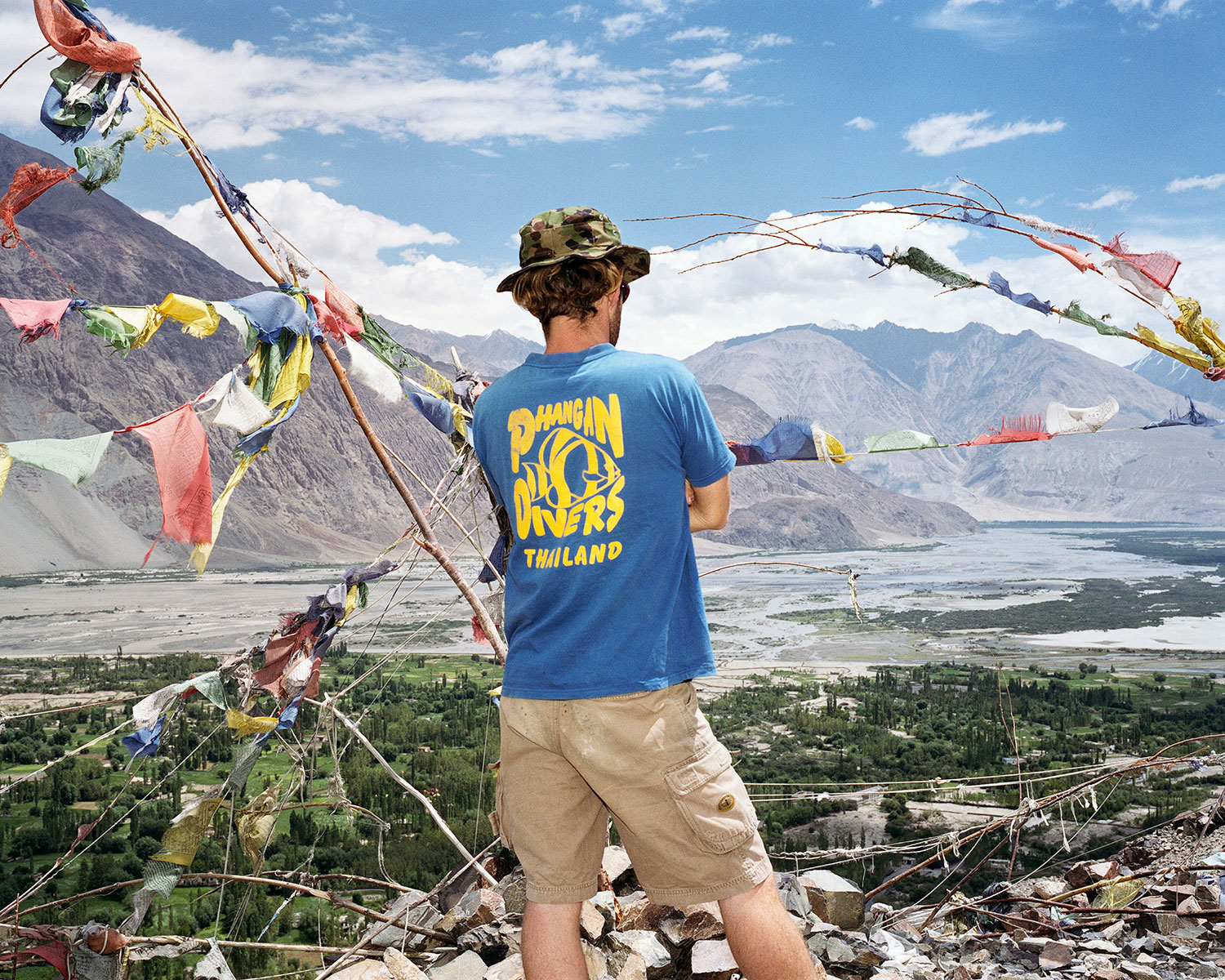 An Austrian tourist looks down the Nubra Valley from a Buddhist temple. He wears a t-shirt of the diver's association of Ko Phangan, Thailand in Hunder, India, August 2007.