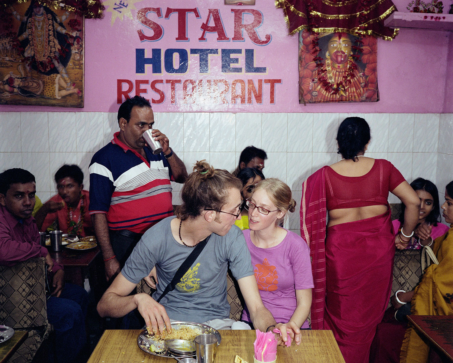 A backpacking couple at a restaurant. The young man has adopted the local custom of eating with the right hand in Varanasi, India, December 2006.