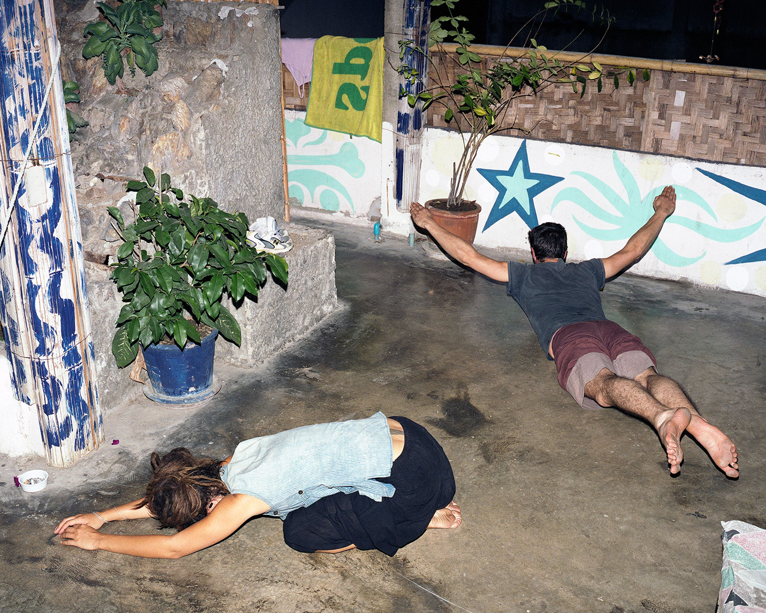 Two French tourists practice yoga to warm up for a session of juggling on the rooftop terrace of an inn in Chiang Mai, Thailand, December 2007.