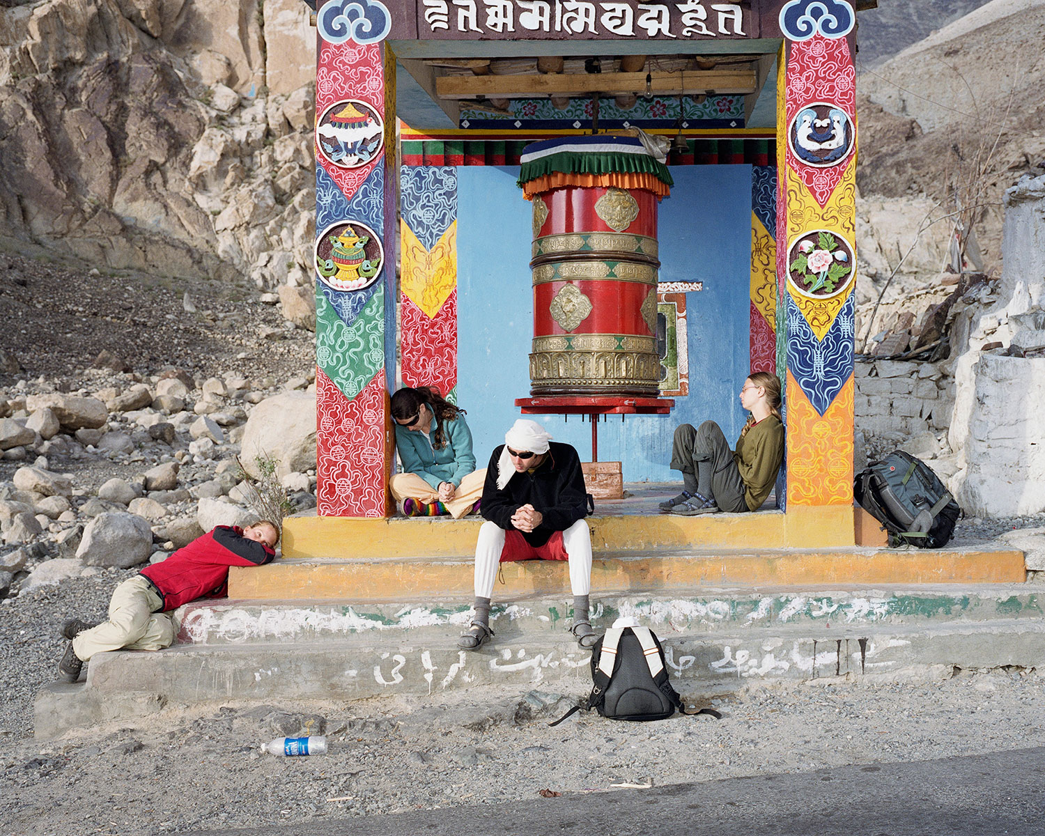 Four Israeli backpackers wait for their bus by a Buddhist prayer wheel in Hunder, India, August 2007.