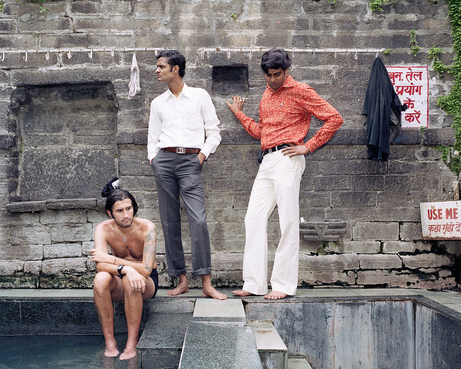 An Italian backpacker and two Indians, who, judging from their dress, are probably visiting from the city, survey the hot spring in a temple in Vashisht, India, August 2007.