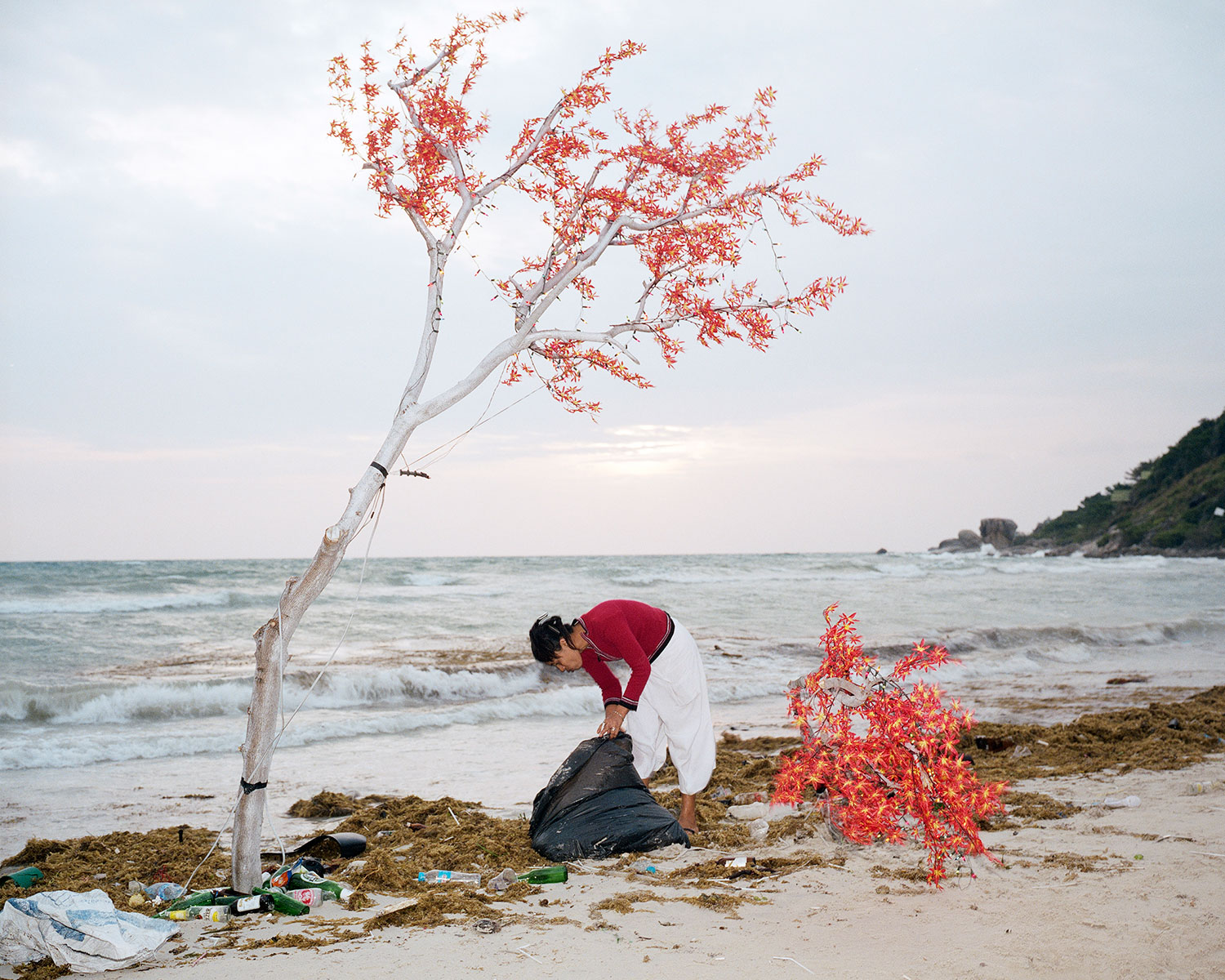 A local Thai woman cleans up the beach after the New Year’s Full Moon Party in Hat Rin, Thailand, January 2008.