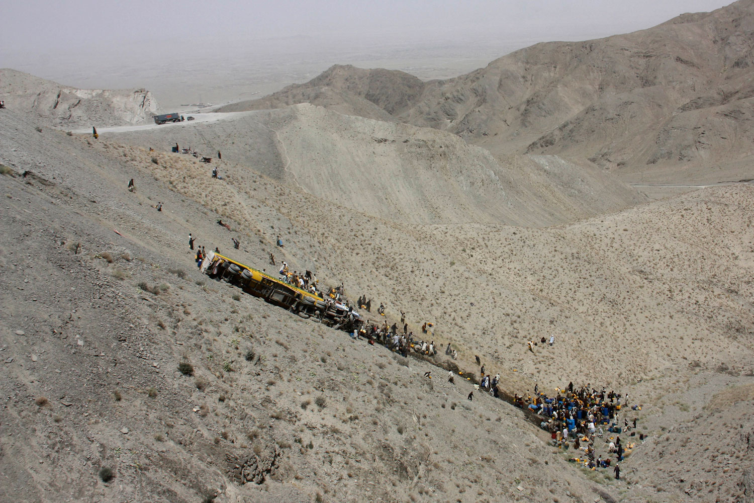 July 12, 2011. Local people rush to collect oil spilled from an overturned NATO oil tanker in Kojak Pass near Chaman, Pakistan along the Afghanistan border. Oil tankers and trucks carry supplies for the NATO forces in neighboring Afghanistan.
