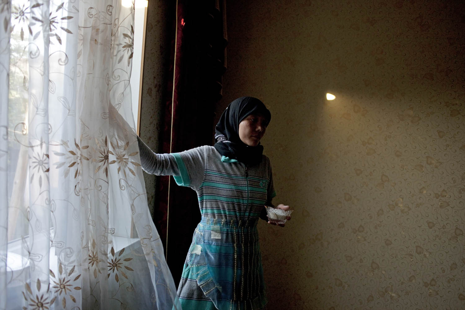 A Uighur woman in the Druzhba neighborhood of Almaty takes a sugar bowl from the window sill to serve guests tea.
