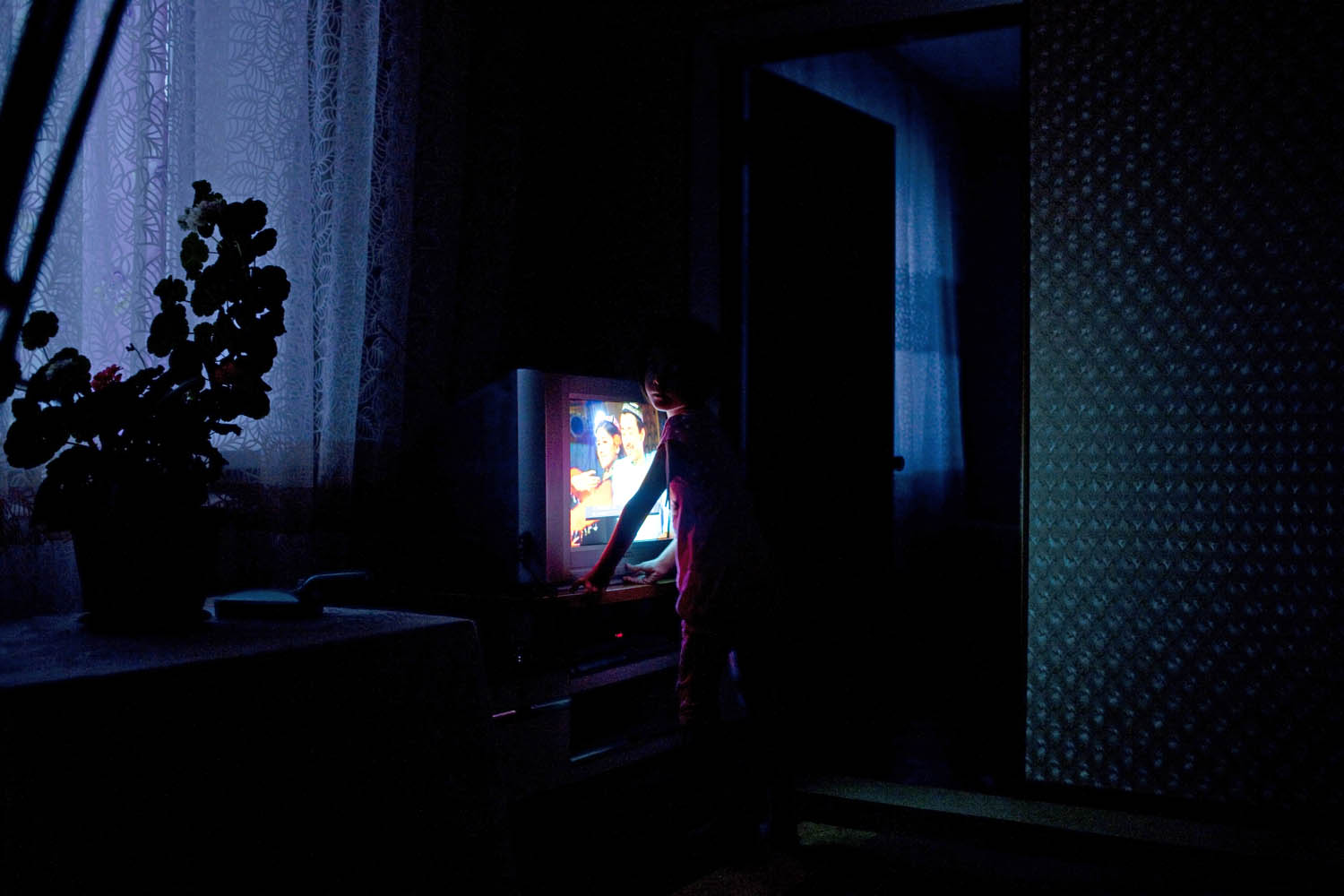 A young Uighur girl watches Uighur dancers on television at home in the Druzhba neighborhood of Almaty.
