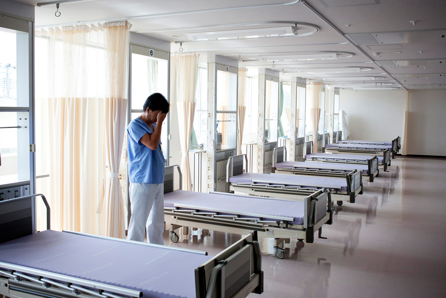 Manabu Takano visits the empty intensive care unit at Watanabe hospital. The unit had to be closed because of the lack of staff. Takano, head nurse at Watanabe, chose not to evacuate and tries to give patients who still come in what care he can.