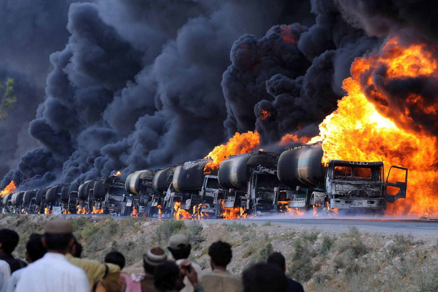 August 22, 2011. Local residents watch the burning NATO supply oil tankers following an attack by gunmen on the main highway at Kolpur village, 25 kilometres (15 miles) south of Quetta, the capital of restive Baluchistan province. Gunmen on motorbikes in southwestern Pakistan set ablaze at least 19 oil tankers carrying fuel for US-led NATO forces in neighbouring Afghanistan.