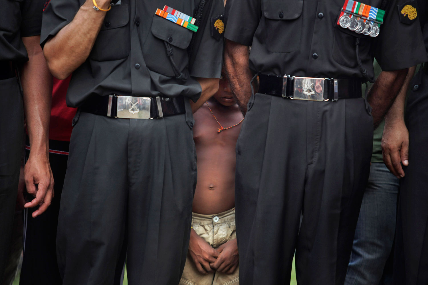 August 22, 2011. A young Indian boy peeps from behind Indian soldiers as they watch the cremation of slain Indian army officer Lt. Navdeep Singh in Gurdaspur, India. Singh was killed, Aug. 20, when Indian troops in Kashmir fought a deadly gunbattle with suspected rebels crossing the military Line of Control from Pakistani-controlled territory.