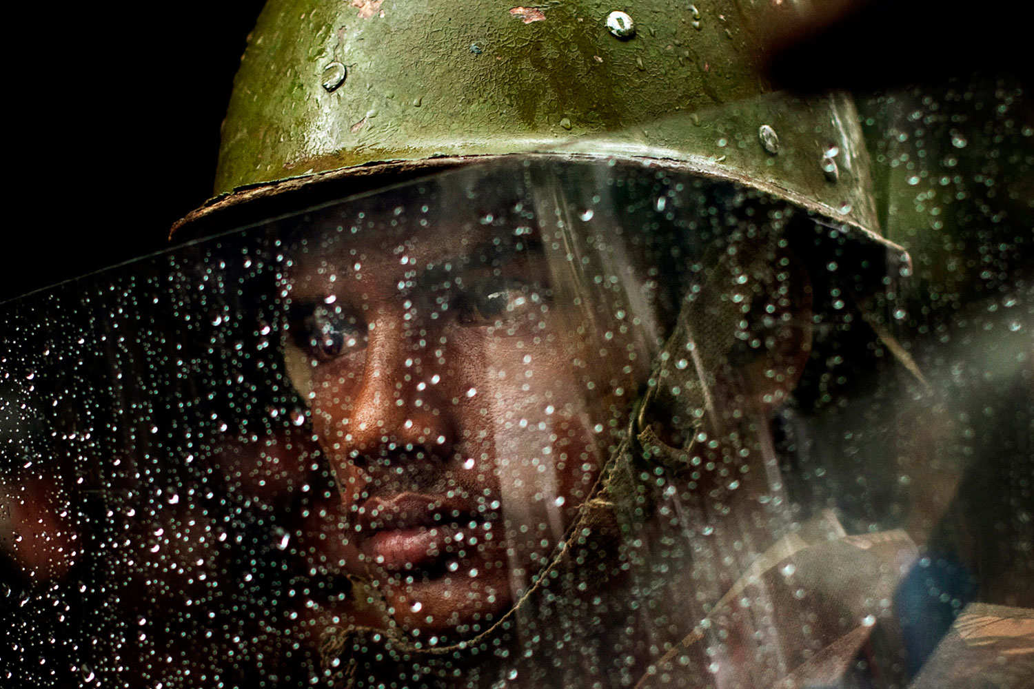 August 11, 2011. An Indian police officer looks from behind his rain covered shield during a monsoon rain shower as he and others stand guard at a protest by the main opposition Bharatiya Janata Party in New Delhi, India. According to local news reports , India's monsoon rain index rose nearly 14 percent in the last week, an increase over the previous period where rain levels were down.
