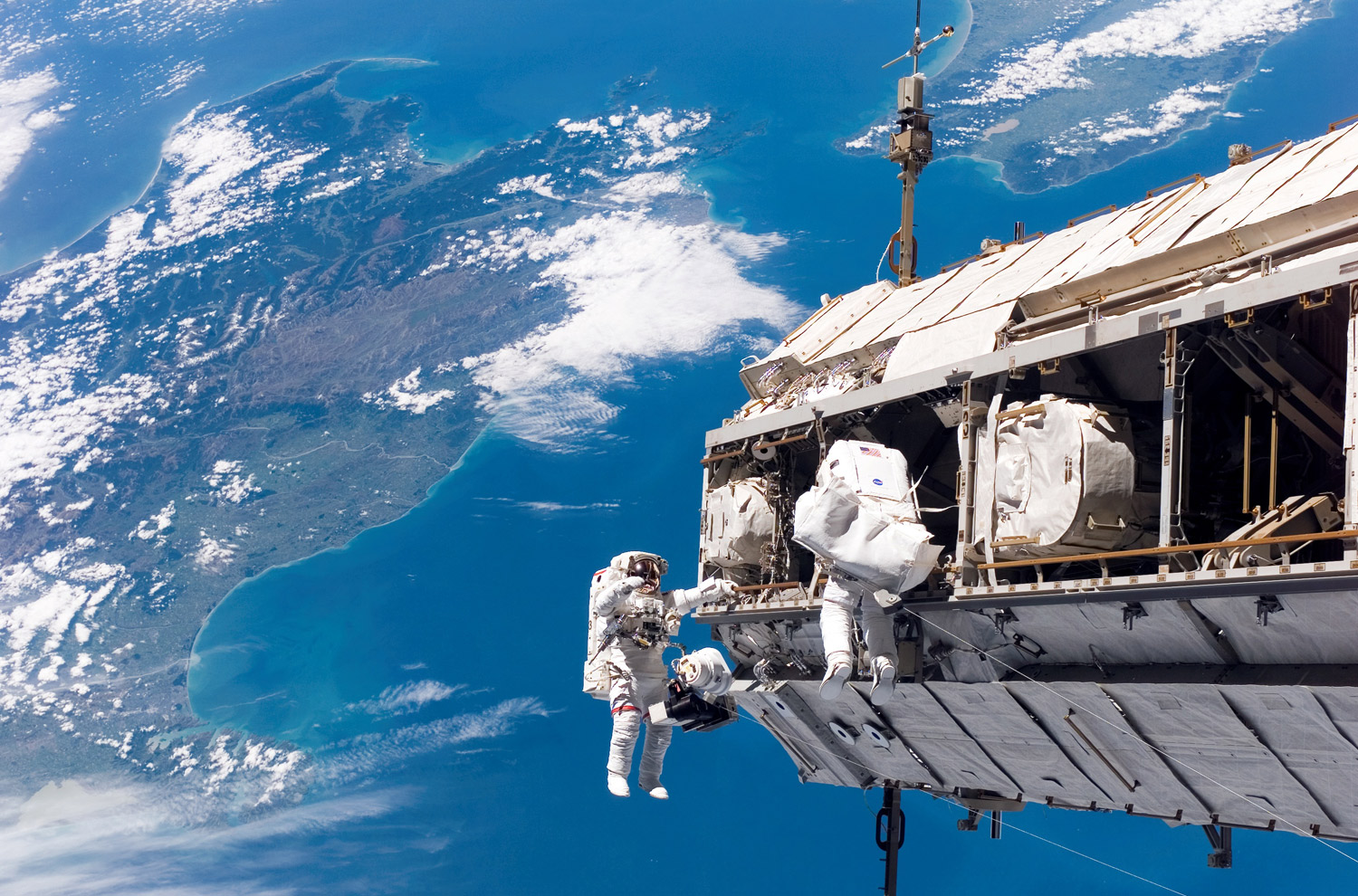 Astronaut Robert L. Curbeam Jr., left, and European Space Agency astronaut Christer Fuglesang participate in an extravehicular activity (space walk) as construction continues on the International Space Station on December 12, 2006. New Zealand and Cook Strait in the Pacific Ocean is visible in the background.