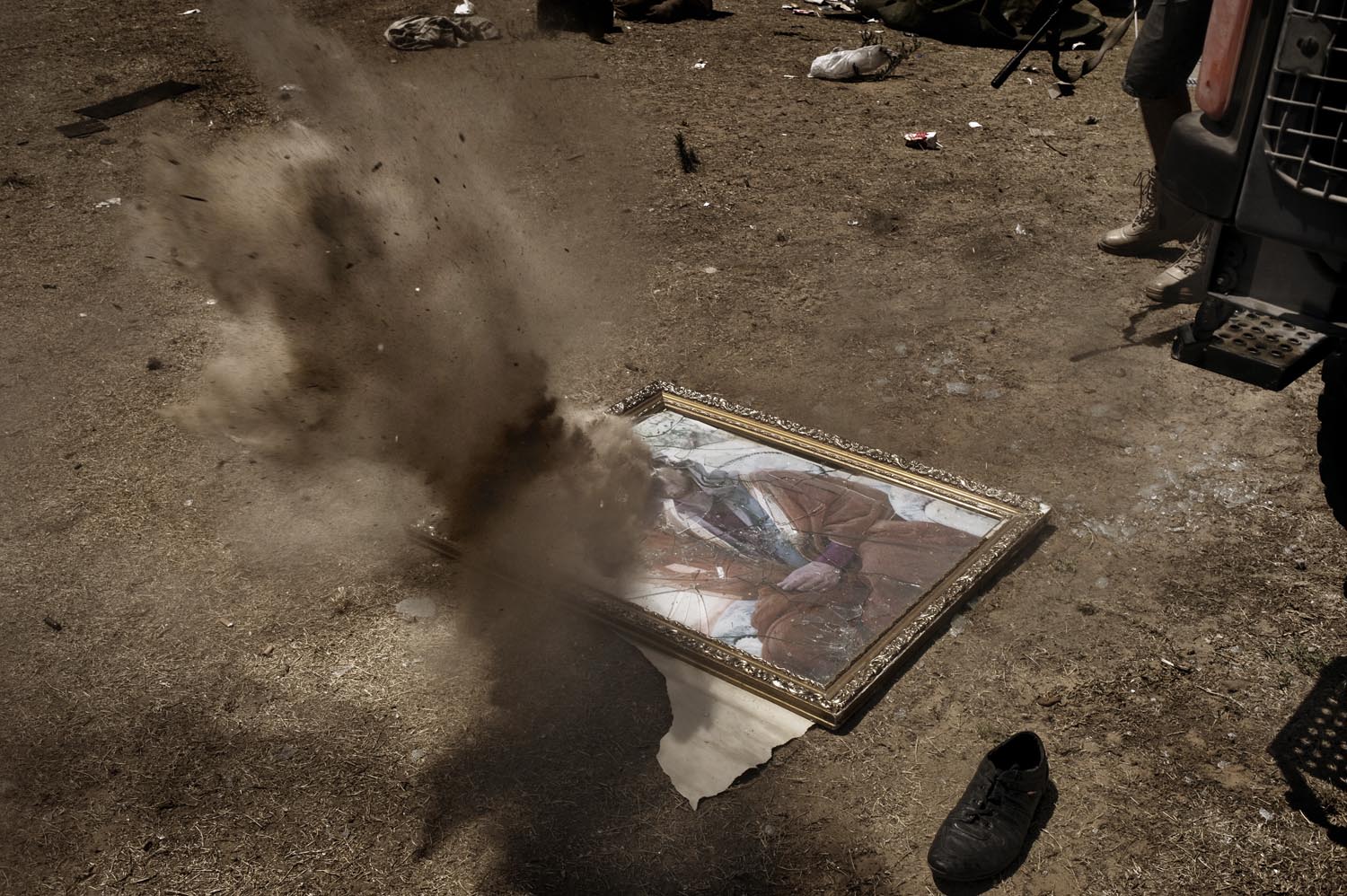 A framed photograph of former Libyan leader Muammar Gaddafi is riddled with machine gun fire as rebels celebrate, August 25, 2011.