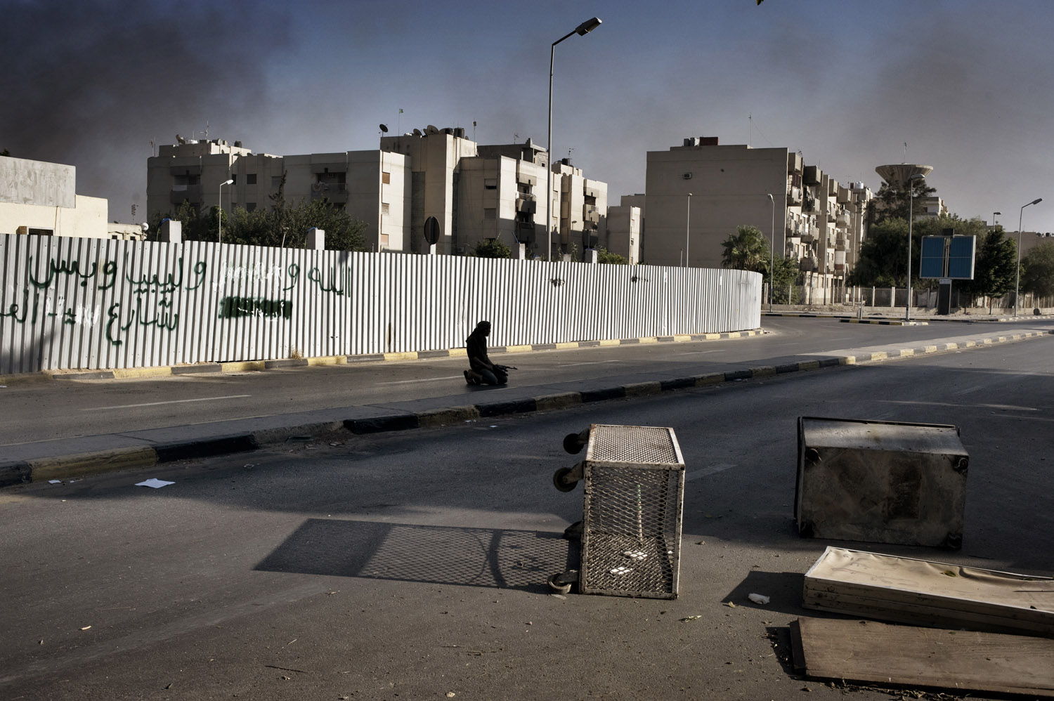 A Libyan rebel soldier prays as smoke from burning buildings fills the air in Tripoli, August 25, 2011.