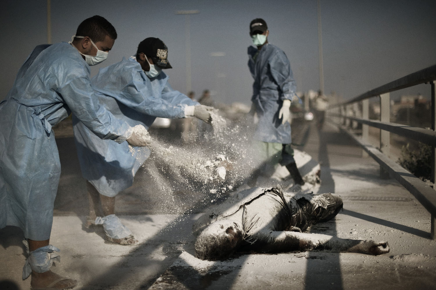 Volunteers sprinkle chemical powder on two corpses in the al-Intisar neighborhood of Tripoli, August 27, 2011. Volunteers have moved throughout the Libyan capital in recent days, removing corpses and garbage that were inaccessible during several days of fighting between rebel forces and Gaddafi loyalists.