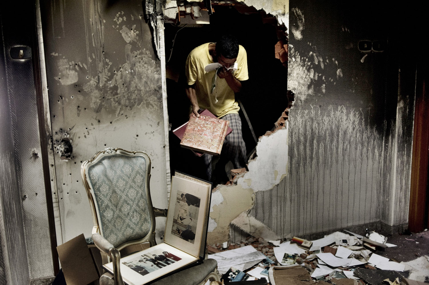 Rebels sift through photo albums inside Gaddafi's home in the Bab al-Aziziya compound of Tripoli, August 28, 2011. The photos were among hundreds strewn about the Gaddafi residence that depicted the Libyan leader with a range of African presidents and dictators.