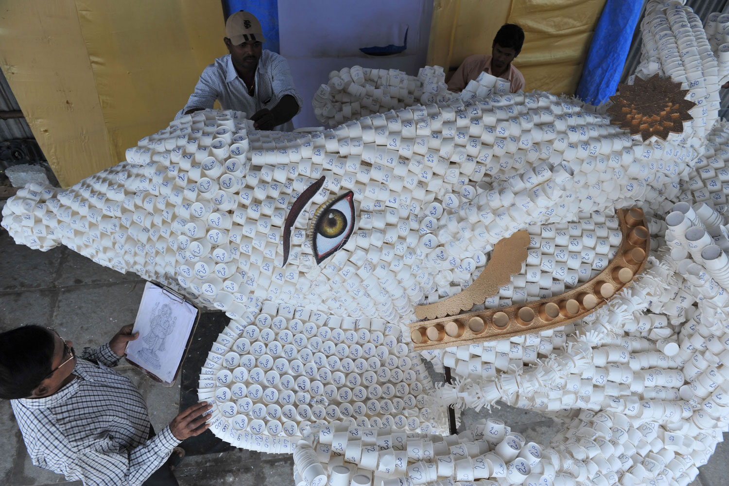 August 29, 2011. An eco-conscious designer gives final instructions for building a environmentally friendly version of Ganesh, the Hindu god of prosperity, in Hyderabad, India. The idol is made mostly of paper cups, which will pose less of an ecological hazard when, as tradition dictates, the decorated model is submerged in the river after the celebration.