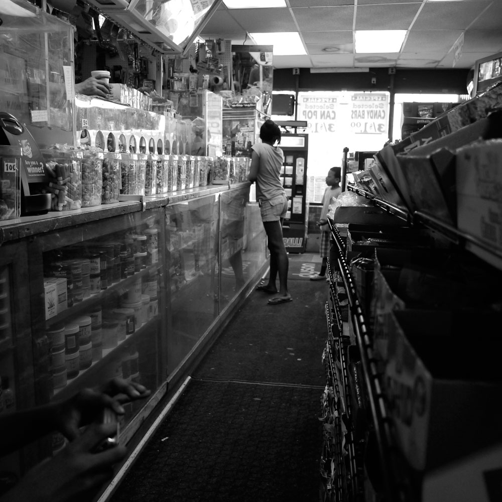 A girl and her brother buy food at the corner store, whose shelves are stocked with a wide variety of chips, candy and soda. There are no unprocessed or natural foods available.